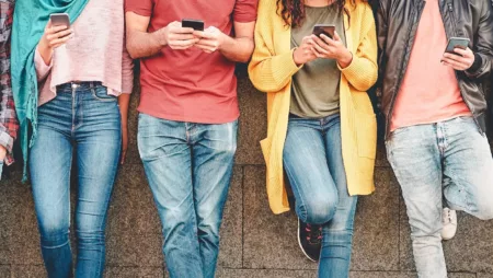 A group of people stand in a line using their phones